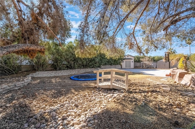 view of yard featuring a trampoline, a storage unit, and a patio