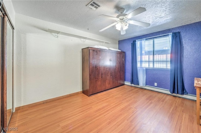 unfurnished bedroom with a textured ceiling, ceiling fan, light hardwood / wood-style floors, and a baseboard radiator