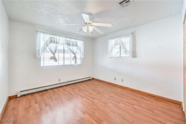 spare room featuring light hardwood / wood-style floors, baseboard heating, a textured ceiling, and ceiling fan