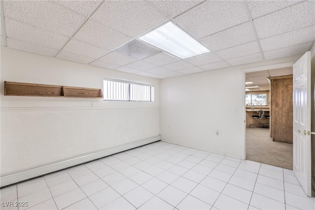 basement featuring a baseboard heating unit and a drop ceiling