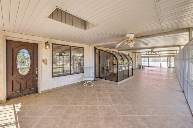 unfurnished sunroom featuring ceiling fan