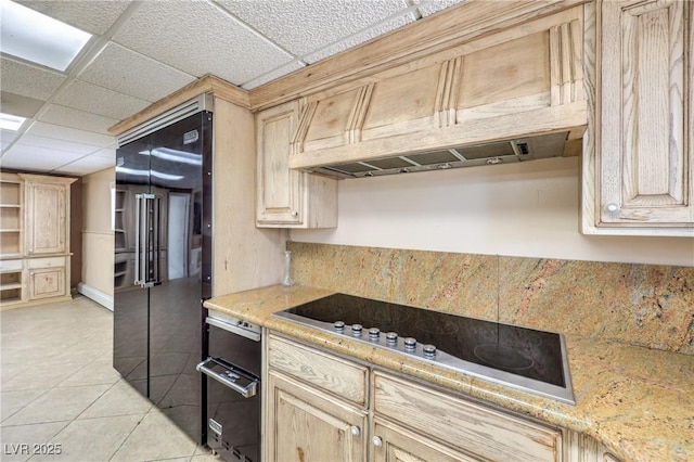 kitchen featuring a paneled ceiling, light tile patterned floors, oven, cooktop, and light brown cabinets