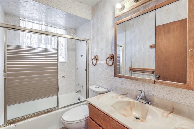 full bathroom featuring toilet, vanity, tile walls, and combined bath / shower with glass door