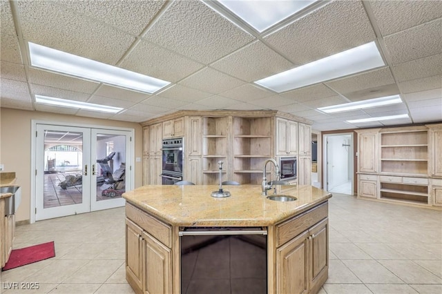 kitchen featuring a paneled ceiling, a center island with sink, french doors, black appliances, and sink