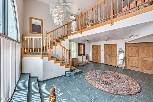 tiled foyer with ceiling fan with notable chandelier