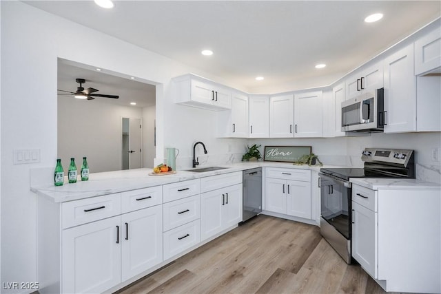 kitchen with sink, white cabinetry, ceiling fan, kitchen peninsula, and appliances with stainless steel finishes