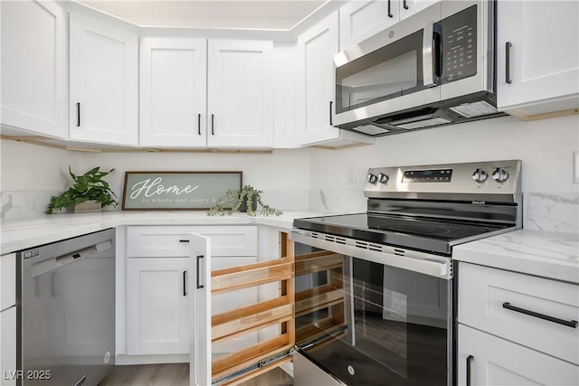 kitchen with stainless steel appliances, light stone countertops, and white cabinets