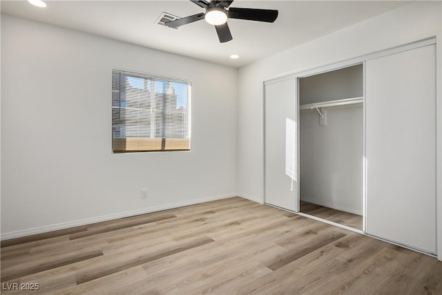 unfurnished bedroom featuring ceiling fan, light hardwood / wood-style floors, and a closet