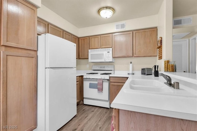 kitchen with sink, white appliances, and light wood-type flooring