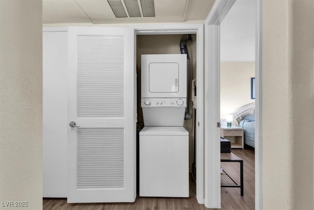 washroom with stacked washer and clothes dryer and wood-type flooring