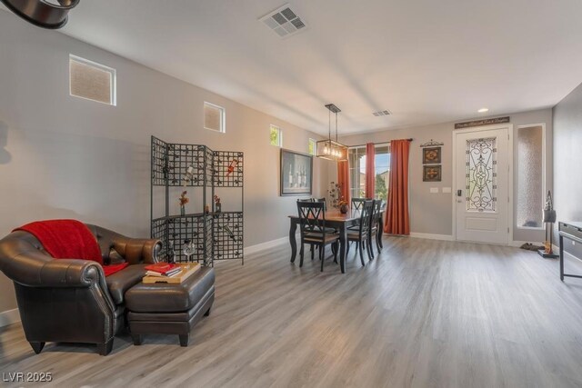 dining room with light wood-type flooring and an inviting chandelier