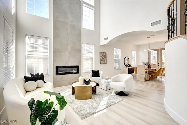 living room featuring a towering ceiling, a fireplace, and a healthy amount of sunlight