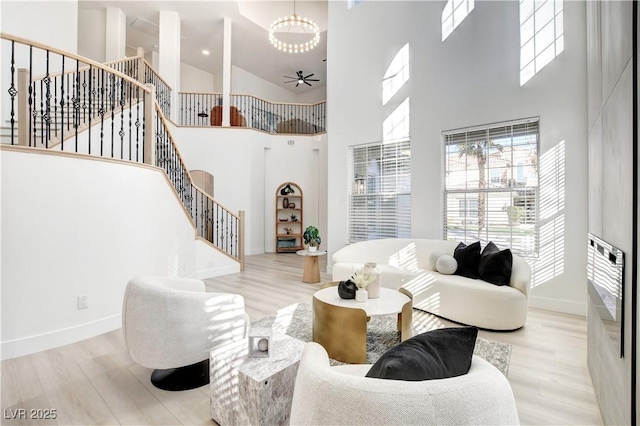 living room featuring a towering ceiling, stairs, baseboards, and wood finished floors