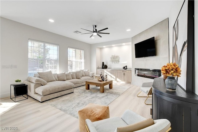 living room with ceiling fan and light hardwood / wood-style flooring