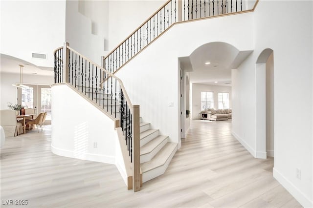 stairs featuring a towering ceiling and hardwood / wood-style floors