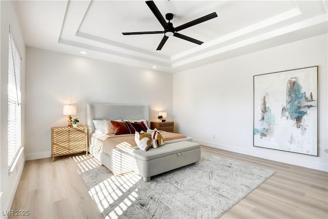 bedroom featuring a raised ceiling, ceiling fan, and light hardwood / wood-style floors