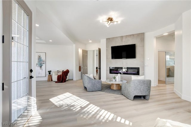 living room with a large fireplace and light hardwood / wood-style flooring