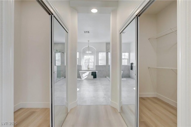 hallway with a notable chandelier and hardwood / wood-style floors