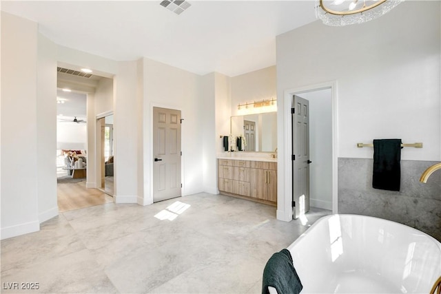 bathroom featuring ceiling fan, a washtub, and vanity