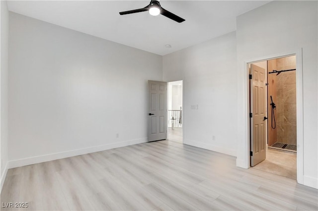 unfurnished bedroom with light hardwood / wood-style floors, a high ceiling, connected bathroom, and ceiling fan