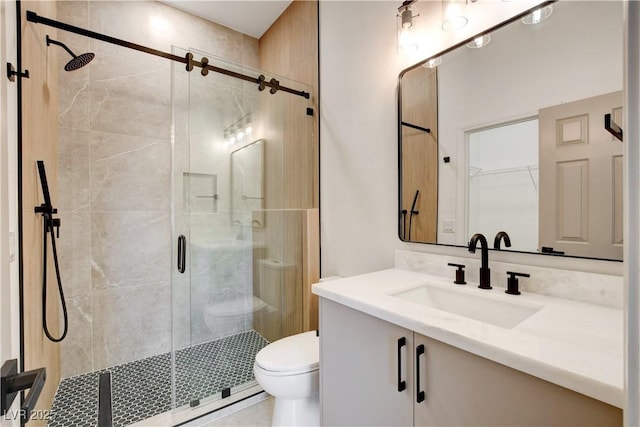 bathroom featuring toilet, a shower with door, and vanity