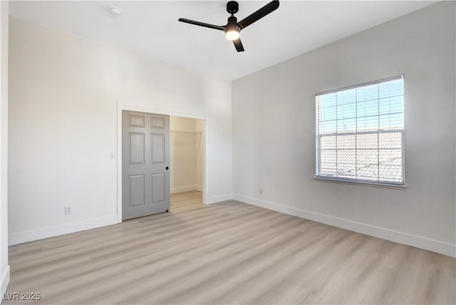 unfurnished bedroom featuring ceiling fan, a spacious closet, a closet, and light hardwood / wood-style floors