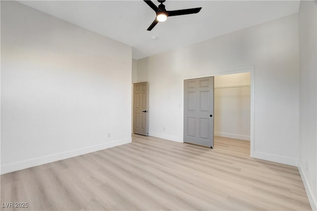 unfurnished bedroom with a closet, ceiling fan, a spacious closet, and light hardwood / wood-style flooring