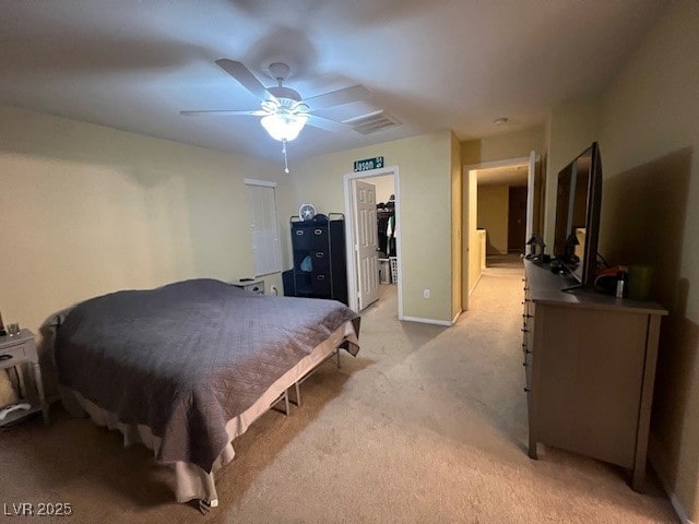 bedroom with a closet, a walk in closet, ceiling fan, and light carpet