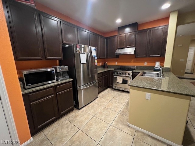 kitchen with appliances with stainless steel finishes, stone counters, light tile patterned floors, sink, and dark brown cabinets