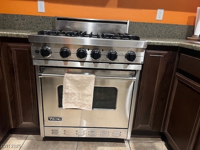 kitchen with dark brown cabinets, designer stove, and light tile patterned flooring