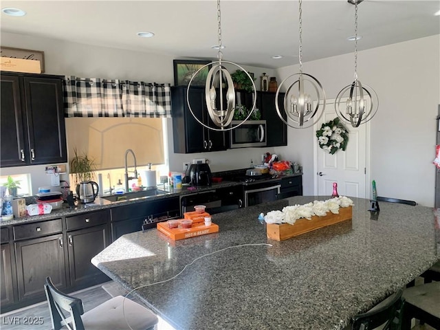 kitchen featuring appliances with stainless steel finishes, a center island, dark stone countertops, sink, and a kitchen breakfast bar