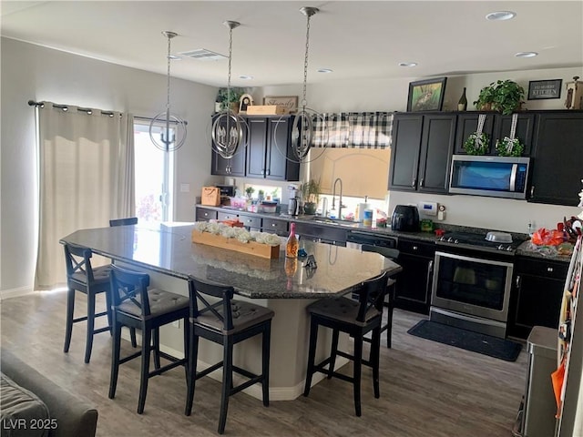 kitchen with a breakfast bar, dark stone countertops, stainless steel appliances, and a center island