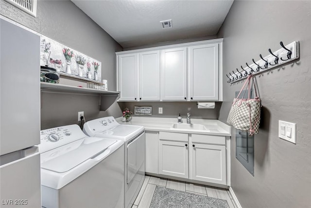 clothes washing area featuring washer and dryer, cabinets, a textured ceiling, and sink