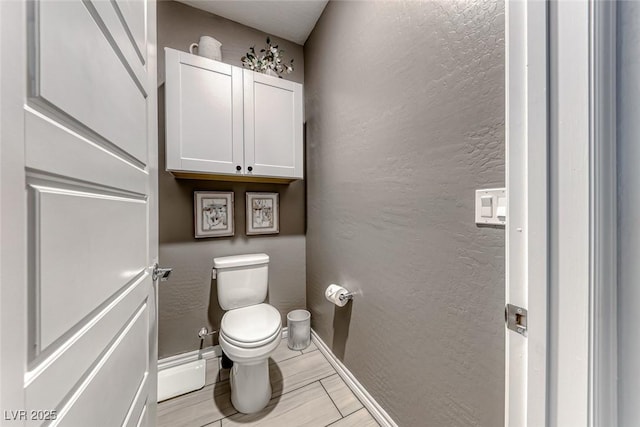 bathroom with toilet and a baseboard heating unit