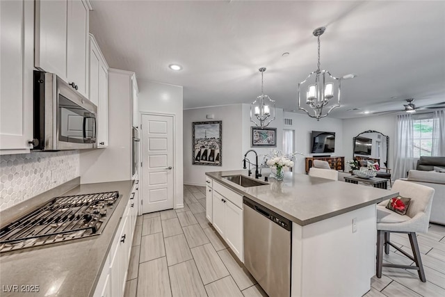 kitchen featuring a center island with sink, white cabinetry, appliances with stainless steel finishes, a breakfast bar area, and sink