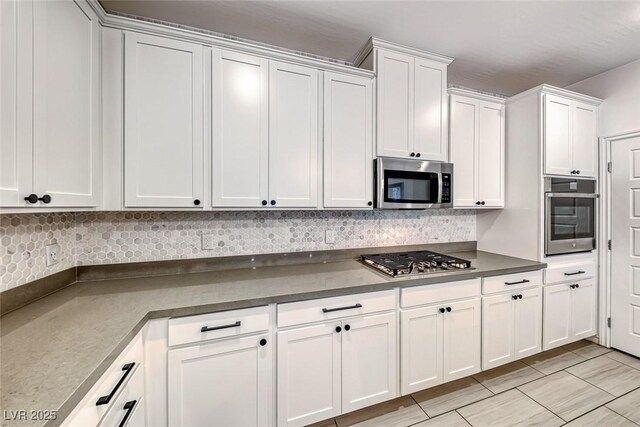 kitchen with white cabinets, stainless steel appliances, and backsplash