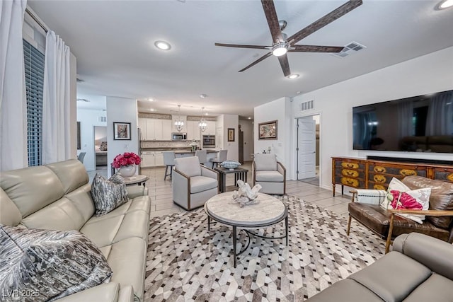 tiled living room with ceiling fan with notable chandelier