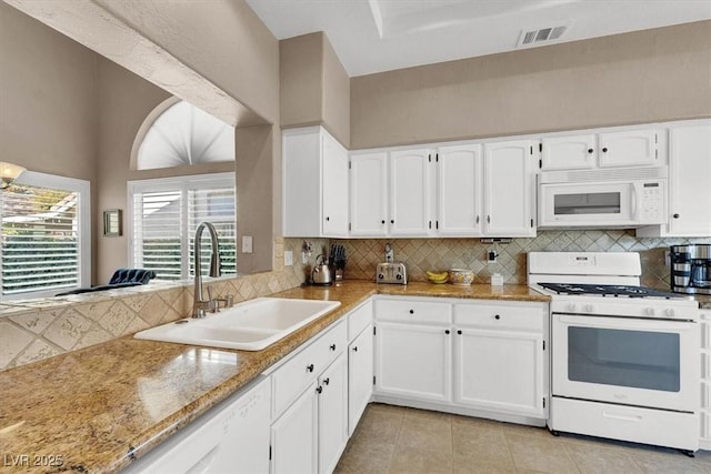 kitchen with sink, white cabinets, light stone counters, white appliances, and backsplash