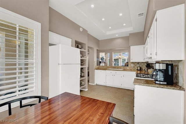 kitchen with white appliances, a tray ceiling, sink, white cabinetry, and built in shelves