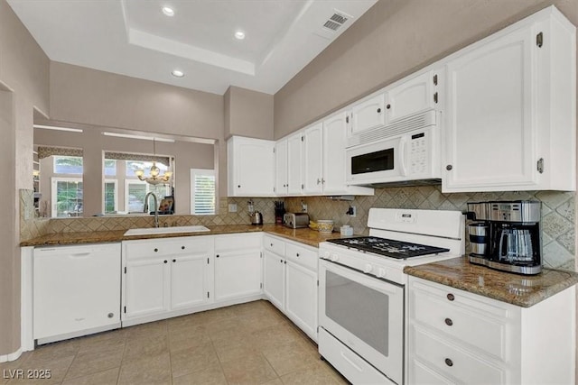 kitchen with sink, white appliances, white cabinetry, and dark stone counters