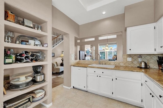 kitchen featuring white cabinets, dishwasher, a chandelier, and sink