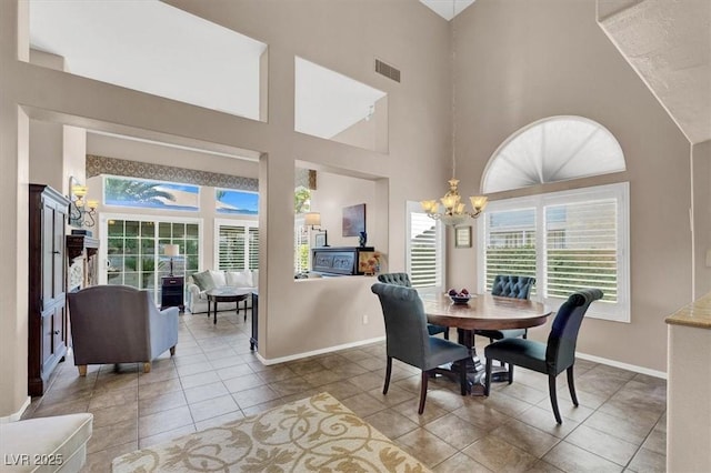 tiled dining space featuring a towering ceiling and an inviting chandelier