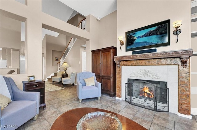 living room featuring a tiled fireplace, light tile patterned flooring, and a high ceiling