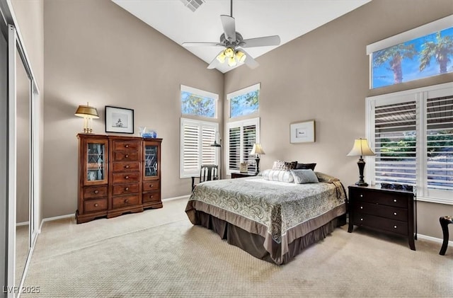 bedroom featuring a closet, high vaulted ceiling, light carpet, and ceiling fan