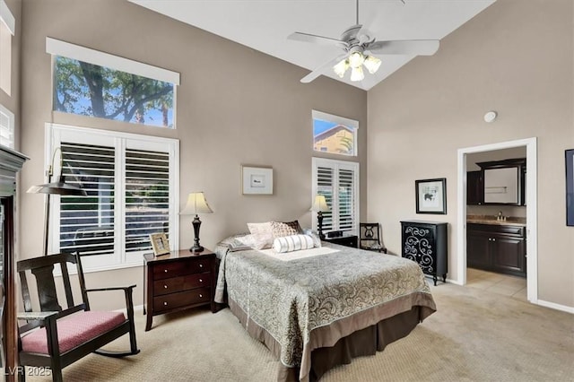 carpeted bedroom with ceiling fan, high vaulted ceiling, and ensuite bath