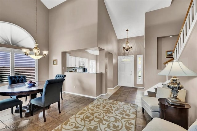 foyer entrance with dark tile patterned floors, high vaulted ceiling, and a notable chandelier