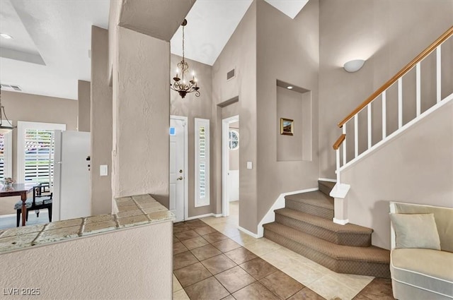 tiled foyer entrance with a notable chandelier and a towering ceiling