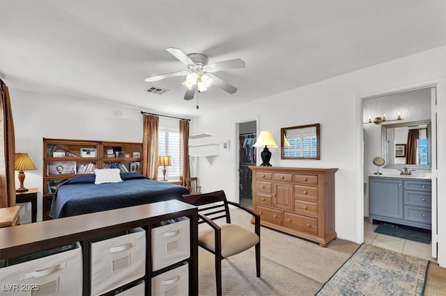 tiled bedroom featuring sink, a spacious closet, ceiling fan, a closet, and ensuite bath