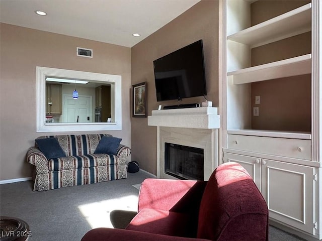 living room with a fireplace, built in shelves, and carpet flooring