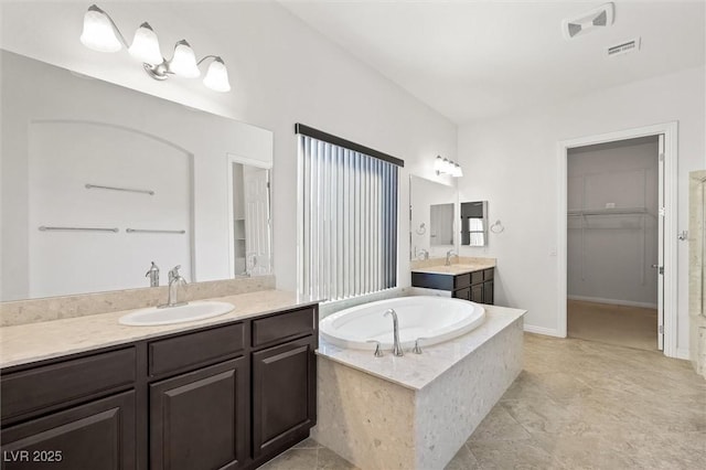 bathroom with tile patterned flooring, tiled tub, and vanity